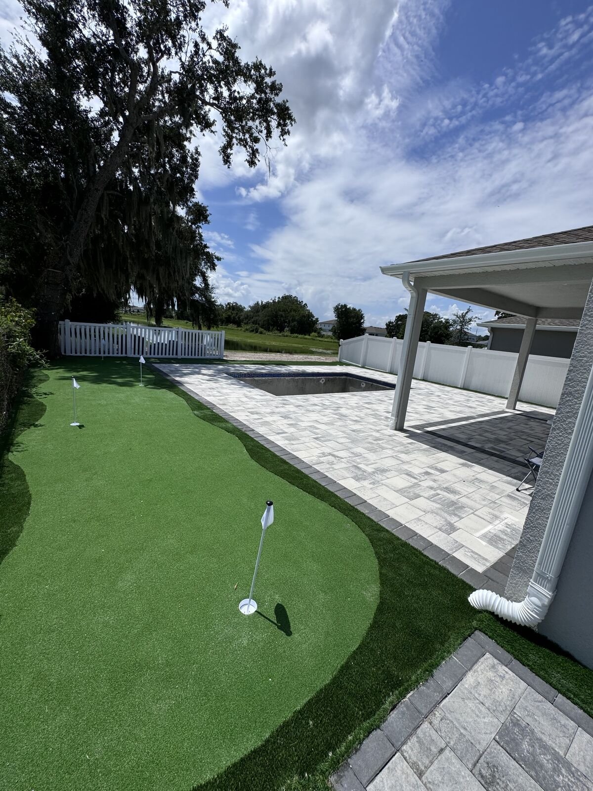 Putting green ao lado da piscina e do patio de pavers