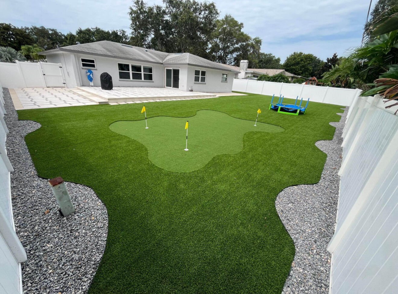 Quintal inteiro com grama sint&eacute;tica e putting green com bandeiras amarelas