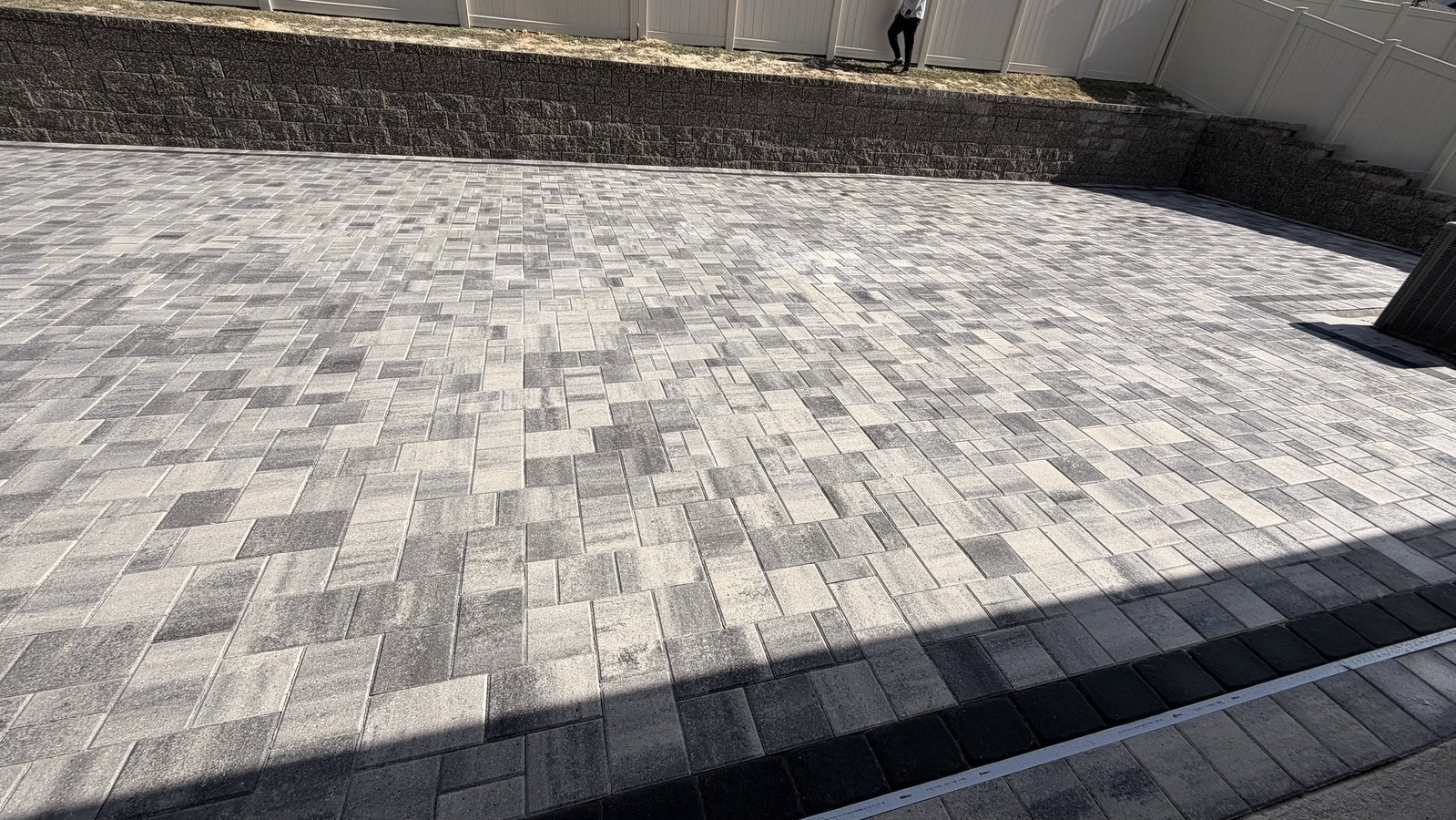 Área de pavers finalizada abaixo de um muro de arrimo em blocos