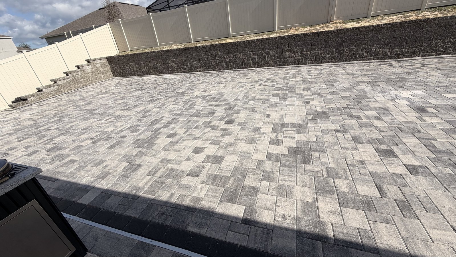 Block retaining wall and gray paver patio, wide view